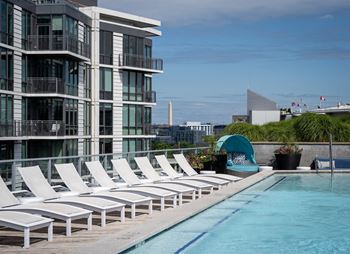 A pool with sun loungers in front of a building.